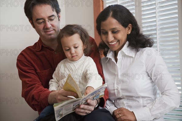 Parents reading book to daughter