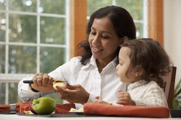 Indian woman slicing apple for daughter