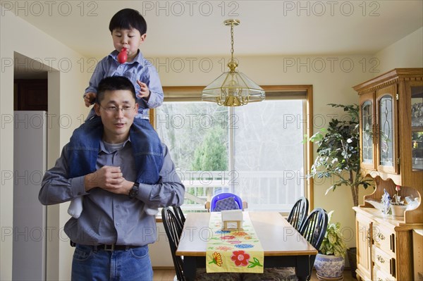 Korean boy riding on father's shoulders