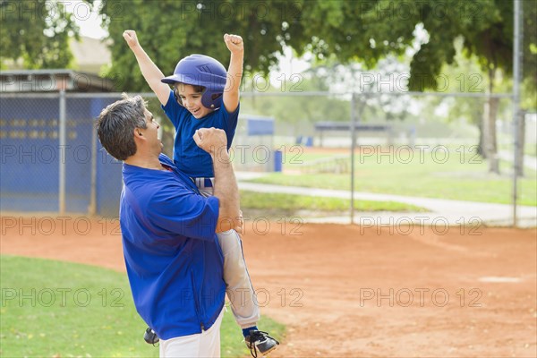 Hispanic coach and young baseball player cheering