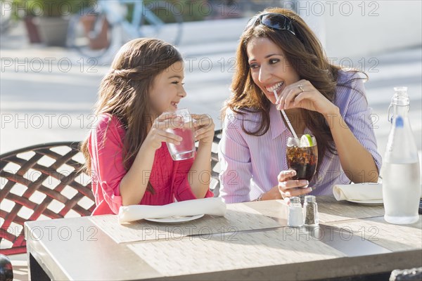 Hispanic mother and daughter eating at cafe