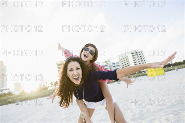 Hispanic mother and daughter playing on beach