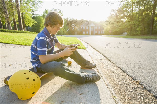 Caucasian boy text messaging on cell phone