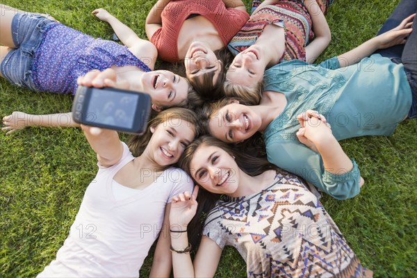 Caucasian friends laying in grass taking self-portrait