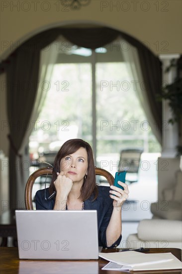 Caucasian businesswoman holding cell phone and looking up