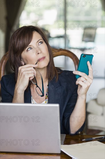 Caucasian businesswoman holding cell phone and looking up