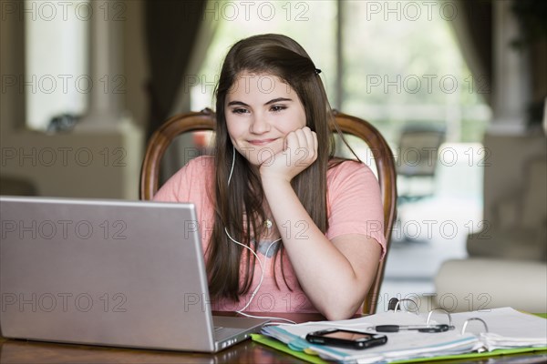 Caucasian girl using laptop and listening to mp3 player