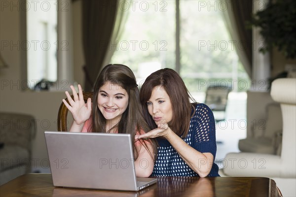 Caucasian mother and daughter having video chat on laptop