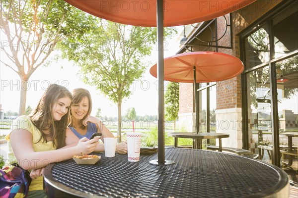 Caucasian mother and daughter looking at cell phone together