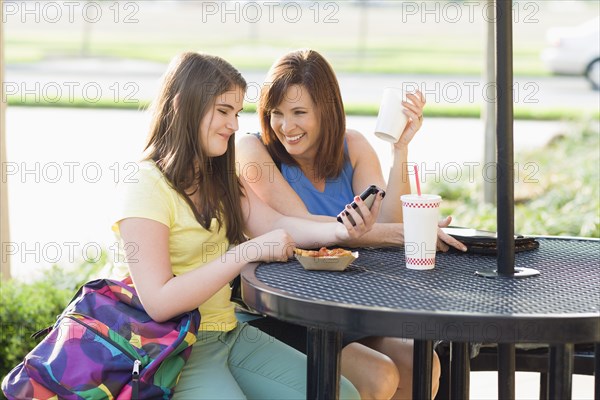 Caucasian mother and daughter looking at cell phone together