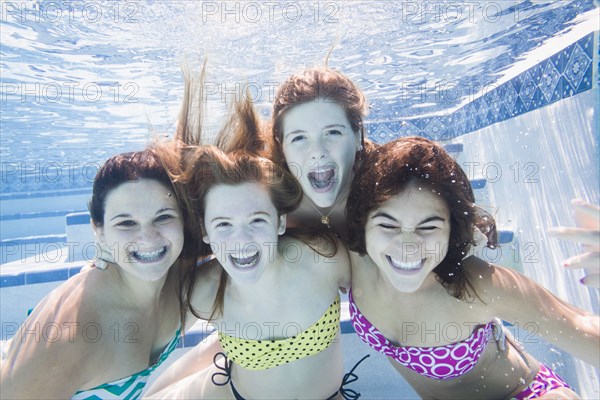 Smiling Caucasian teenagers underwater in swimming pool