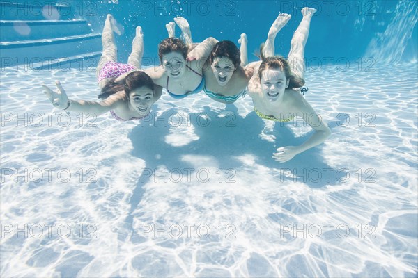 Smiling Caucasian teenagers underwater in swimming pool