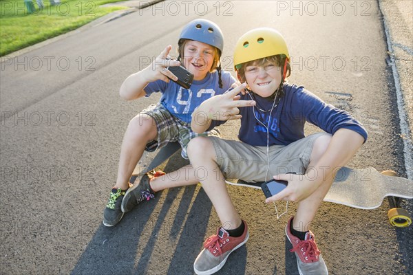 Caucasian boys sitting on skateboards and making gestures