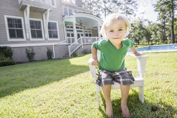 Caucasian boy sitting in chair in backyard