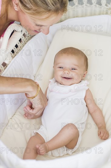 Caucasian mother looking at baby in bassinet