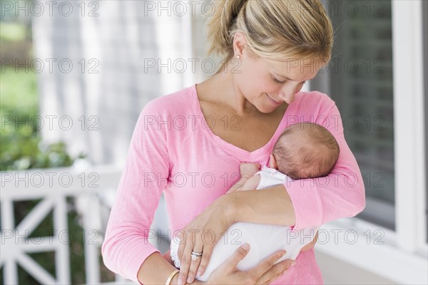 Caucasian mother holding baby on porch