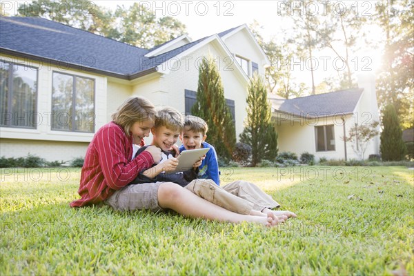 Caucasian boys using digital tablet on lawn