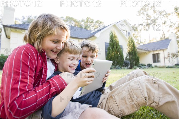 Caucasian boys using digital tablet on lawn