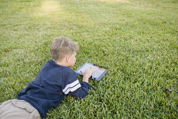 Caucasian boy using digital tablet on lawn