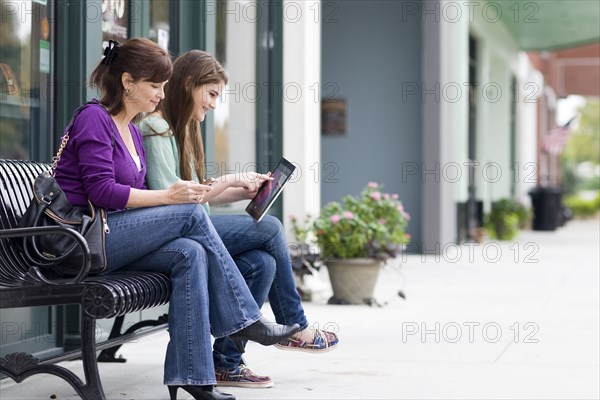 Caucasian mother and daughter on city bench