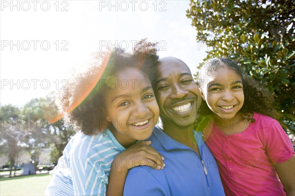Father and daughters smiling in park