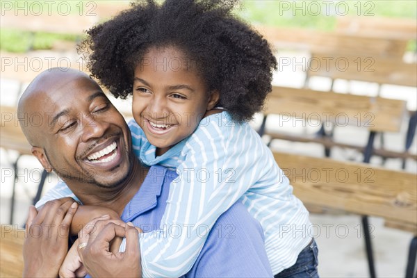 Father and daughter smiling on park bench