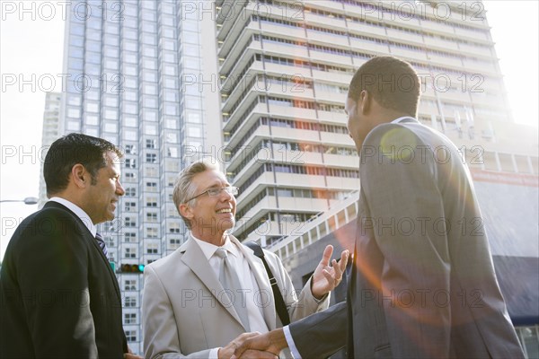 Businessmen shaking hands on city street