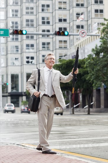 Caucasian businessman hailing taxi on city street