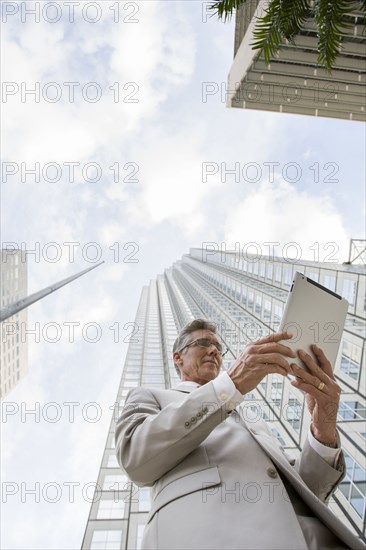 Caucasian businessman with tablet computer on city street