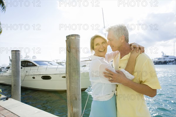 Caucasian couple hugging on dock