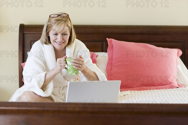 Caucasian woman using laptop on bed