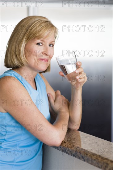 Caucasian woman drinking water in kitchen