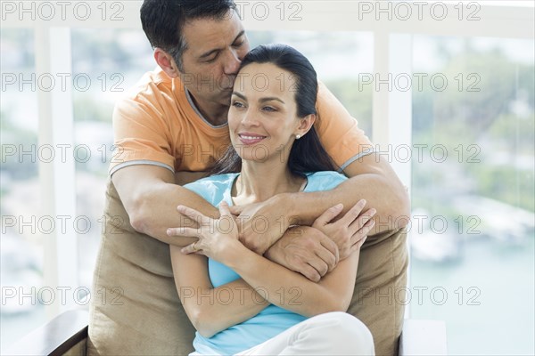 Hispanic couple hugging in armchair