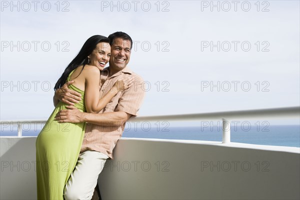 Hispanic couple hugging on boat deck