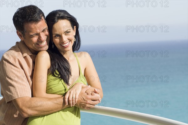 Hispanic couple hugging on boat deck