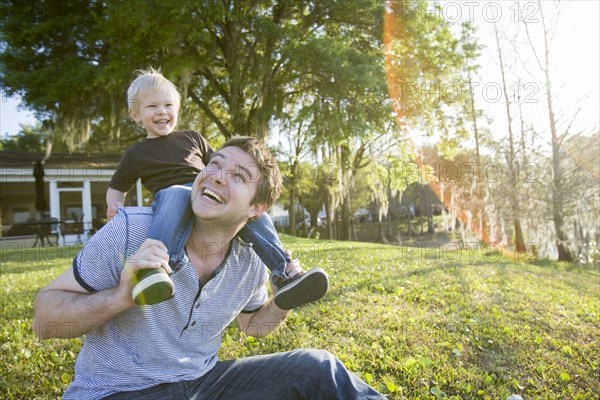 Caucasian father carrying son on shoulders in backyard