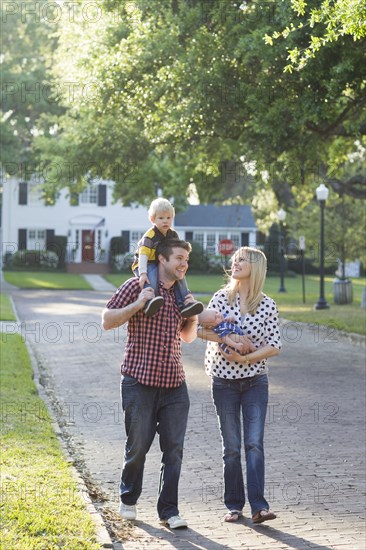 Caucasian family walking along neighborhood street