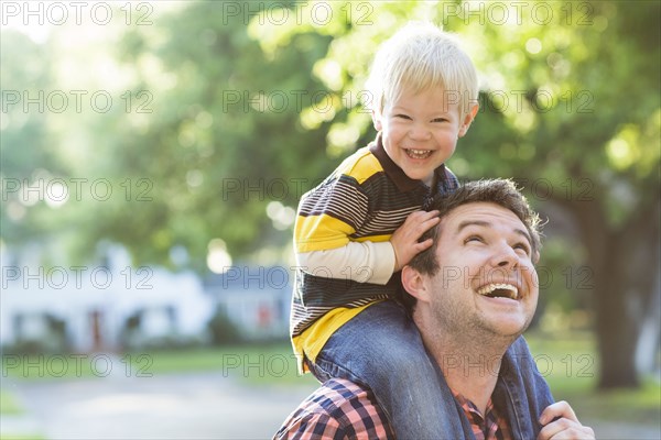 Caucasian father carrying son on shoulders