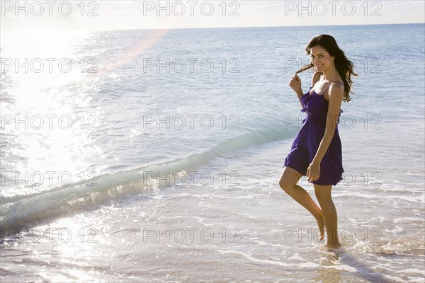 Hispanic woman walking in surf on beach