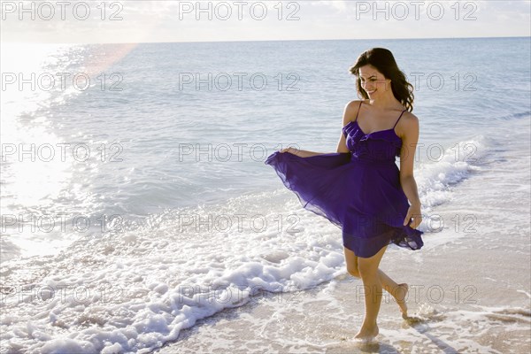 Hispanic woman walking in surf on beach