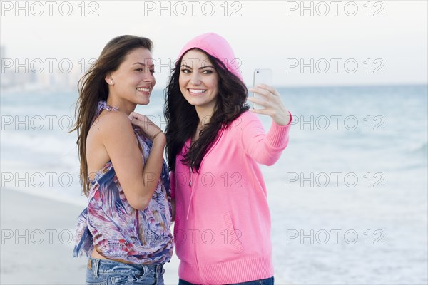 Women taking pictures together on beach