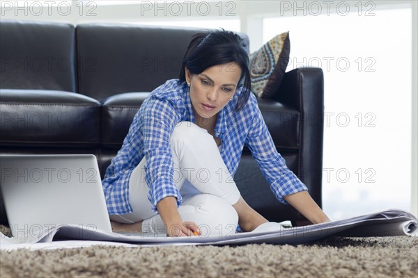 Hispanic woman examining blueprints in living room