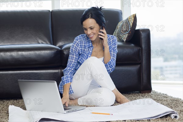 Hispanic woman examining blueprints in living room