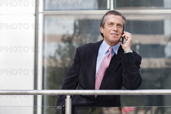 Caucasian businessman on cell phone on balcony