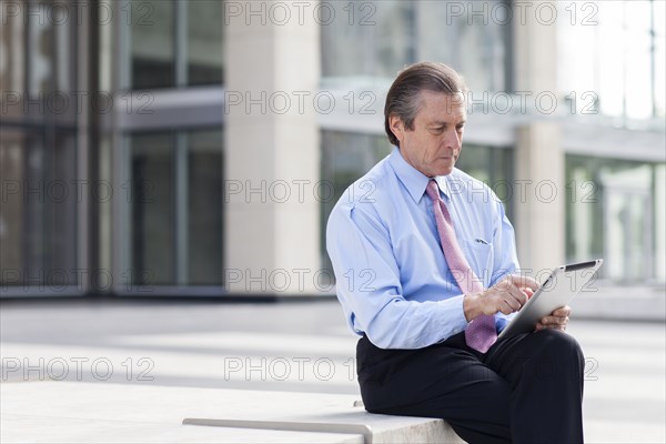 Caucasian businessman using digital tablet in courtyard