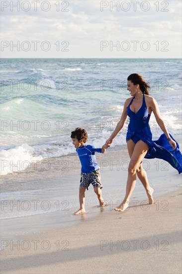 Caucasian mother and son walking on beach