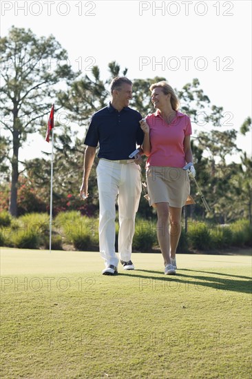 Caucasian couple playing golf on course