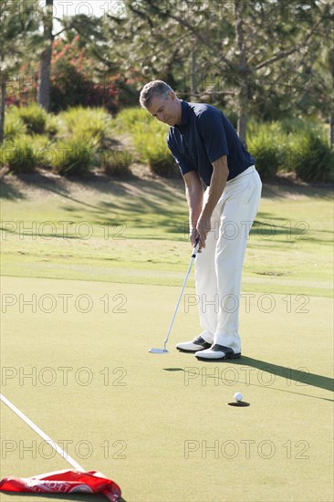 Caucasian man putting on golf course