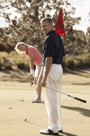 Caucasian couple playing golf on course