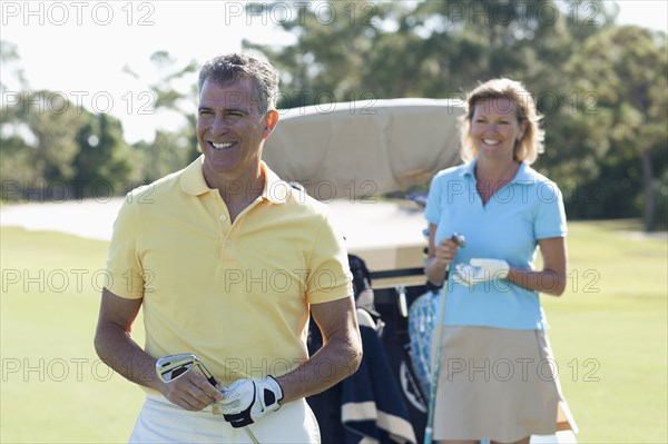 Caucasian couple playing golf on course